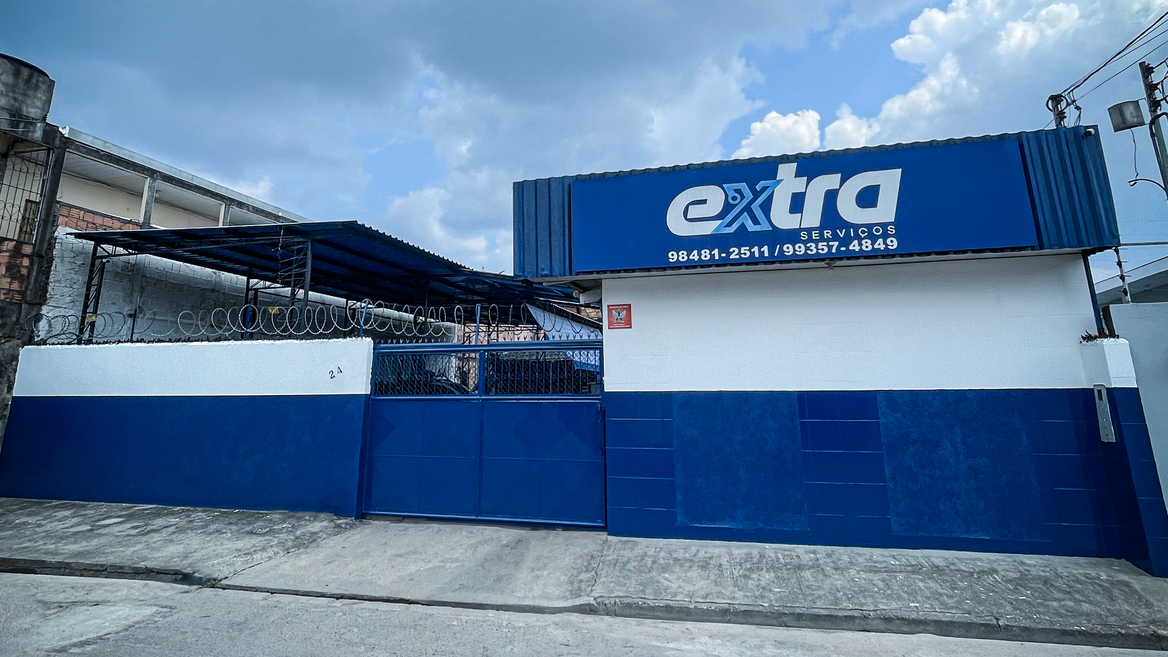 Fachada da Extra Serviços em Manaus, pintada em azul e branco com o logo da empresa e os telefones de contato